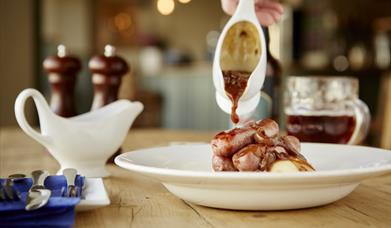 Gravy being poured over sausages