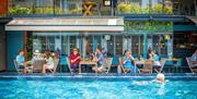 Bristol Lido - person swimming in pool and people dining by restaurant