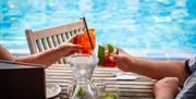 The Lido Restaurant two people holding cocktails by the pool