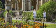 Two children in white t-shirts and shorts strolling round the gardens of a mansion