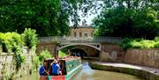 A canal boat sailing beneath a bridge in Sydney Gardens, Bath